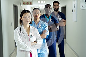 Portrait of diverse group of healthcare workers wearing cancer ribbons standing in hospital corridor