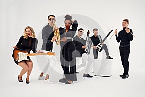 Portrait of diverse group of young people musical band playing with instruments - isolated on white background.