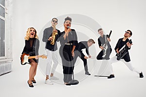 Portrait of diverse group of young people musical band playing with instruments - isolated on white background.