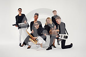 Portrait of diverse group of young people musical band playing with instruments - isolated on white background.