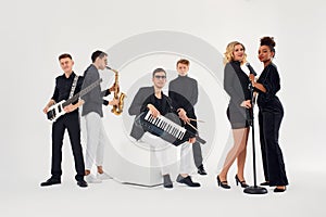 Portrait of diverse group of young people musical band playing with instruments - isolated on white background.