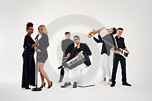 Portrait of diverse group of young people musical band playing with instruments - isolated on white background.