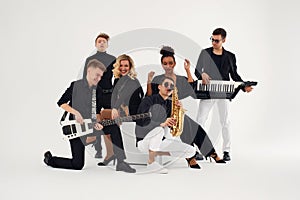 Portrait of diverse group of young people musical band playing with instruments -  on white background.
