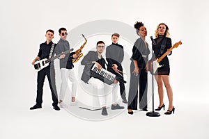 Portrait of diverse group of young people musical band playing with instruments -  on white background.