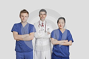 Portrait of diverse healthcare workers standing with hands folded over gray background