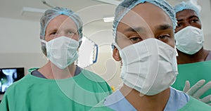 Portrait of diverse male surgeons wearing face masks in operating theatre, slow motion