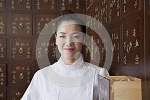 Portrait of Doctor In Front of Traditional Chinese Medicine Cabinet