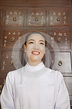 Portrait of Doctor In Front of Traditional Chinese Medicine Cabinet