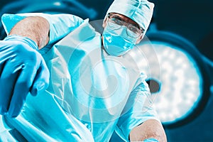 Portrait of a doctor in a mask on a background of surgical lamps. Medicine concept