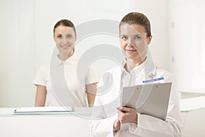 Portrait of doctor and nurse standing at checkout counter in hospital