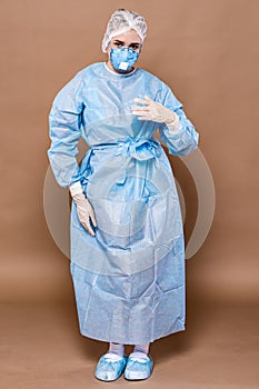 Portrait of a doctor`s girl on a peach background in a protective suit