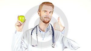 Portrait of a doctor showing an apple with the thumb up , white background