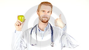 Portrait of a doctor showing an apple with the thumb up , white background
