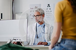 Portrait of doctor talking with tennage girl patient, during visit. Concept of preventive health care for adolescents.