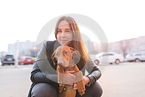 Portrait of a dog and a girl`s owner against the background of the sunset. A walk with a pet in the city