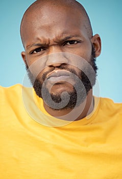 Portrait, doubt and expression with a black man in studio on a blue background feeling annoyed or frustrated. Face