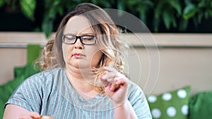 Portrait of doubtful fat woman on diet refusing from unhealthy burger fast food