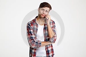 Portrait of a doubtful young man talking on mobile phone