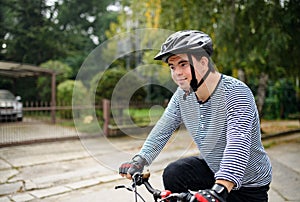 Portrait of down syndrome adult man with bicycle cycling outdoors on street.