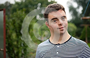 Portrait of down syndrome adult man standing outdoors in garden.