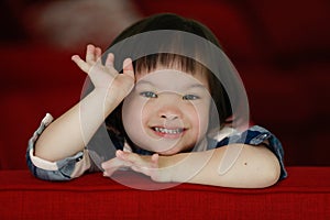 Portrait of a down syndrome baby girl smiling with happiness and play with camera