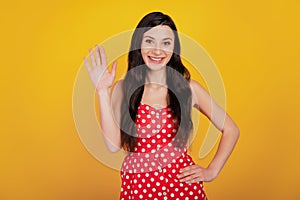 Portrait of dream woman wave hand wear dotted red dress on yellow background