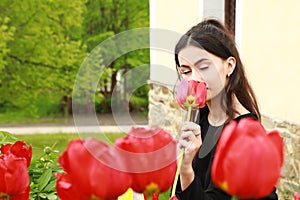 Portrait of dreaming pretty young teen girl behind red tulips