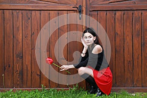 Portrait of dreaming pretty young teen girl with red tulip by gate