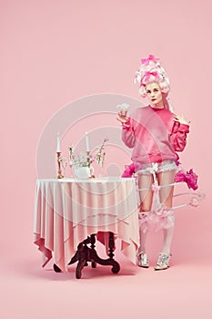 Portrait with dreaming princess wearing fancy clothes holding cocktail over studio background. Pink style birthday