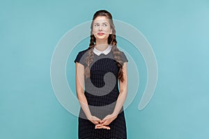 Dreamy attractive smiling woman with braids standing and looking away, planning, pondering.