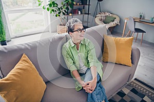 Portrait of dreamy happy pensioner attractive pensioner woman looking far away hug her knees indoors inside office