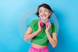Portrait of dreamy looking empty space youngster girl hold new pink headphones meloman spotify promo isolated on