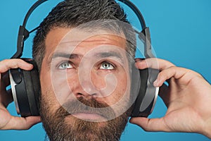 Portrait of dreamy man listening music with headphones. Bearded man in wireless headphones. Leisure, relax and
