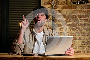 Portrait of a dreamy man sitting at a desk, working on a laptop, thinking about solving a problem, a thoughtful man