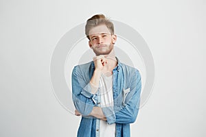 Portrait of dreamy young handsome guy thinking dreaming with hand on chin over white background.