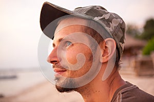 Portrait of a dreamy young man on the ocean in a warm summer day at sunset