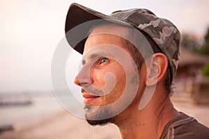 Portrait of a dreamy young man on the ocean in a warm summer day at sunset