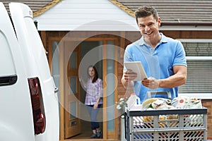 Portrait Of Driver Delivering Online Grocery Order To House Using Digital Tablet