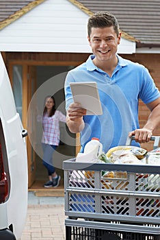 Portrait Of Driver Delivering Online Grocery Order To House Using Digital Tablet