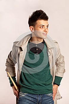 Portrait of a drummer with drum stick wearing a coat and greeen shirt in studio