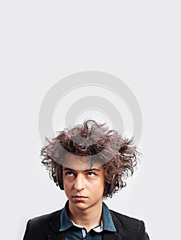 Portrait of dubious young man with awesome hairdo, with headphones, looking pensive, isolated on white background.