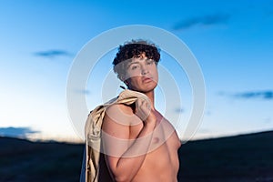 Portrait during dusk of non binary male with naked torso