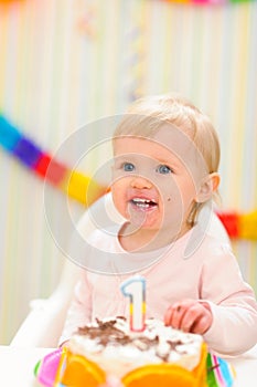 Portrait of eat smeared baby with birthday cake photo