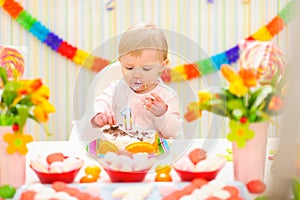 Portrait of eat smeared baby eating birthday cake photo