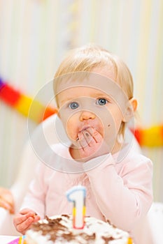 Portrait of eat smeared baby eating birthday cake