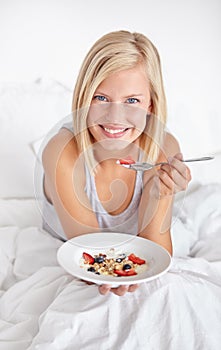 Portrait, eating and woman with breakfast in bed with healthy food, fruit and oats for nutrition in diet. Happy, girl