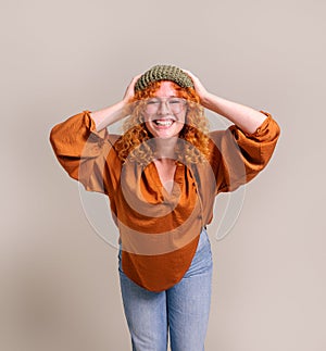 Portrait of ecstatic beautiful woman with head in hands smiling and standing on white background