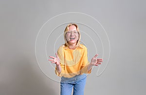 Portrait of ecstatic businesswoman in eyeglasses gesturing and laughing at camera on white background