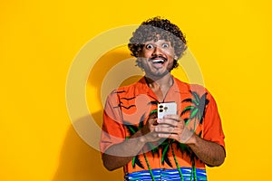 Portrait of ecstatic guy with afro hair wear shirt impressed by fast internet connection on smartphone  on