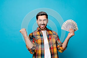 Portrait of ecstatic guy with stylish stubble wear checkered shirt holding money win gambling scream yes isolated on